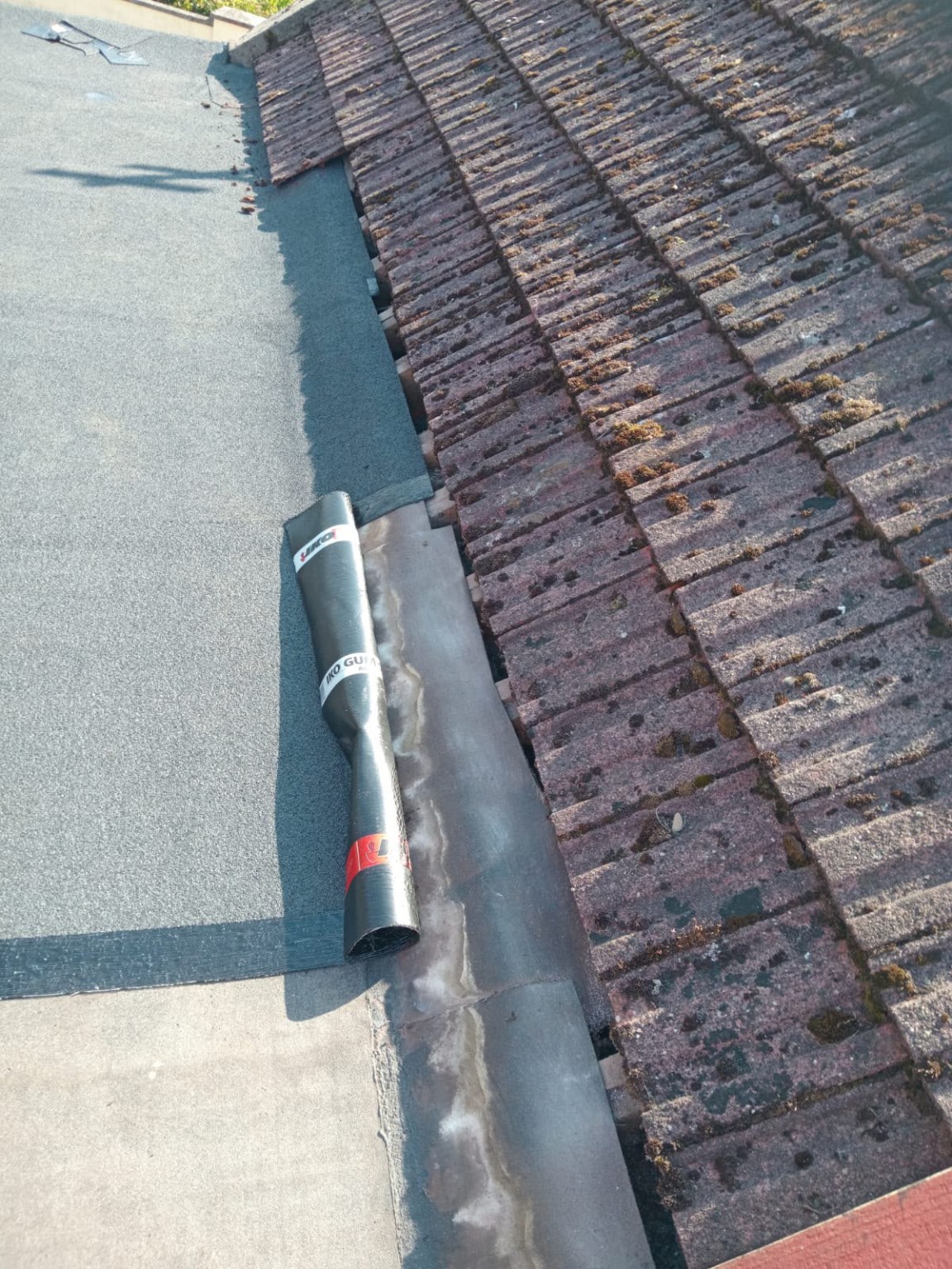 Finished felt roof beside an existing tiled roof