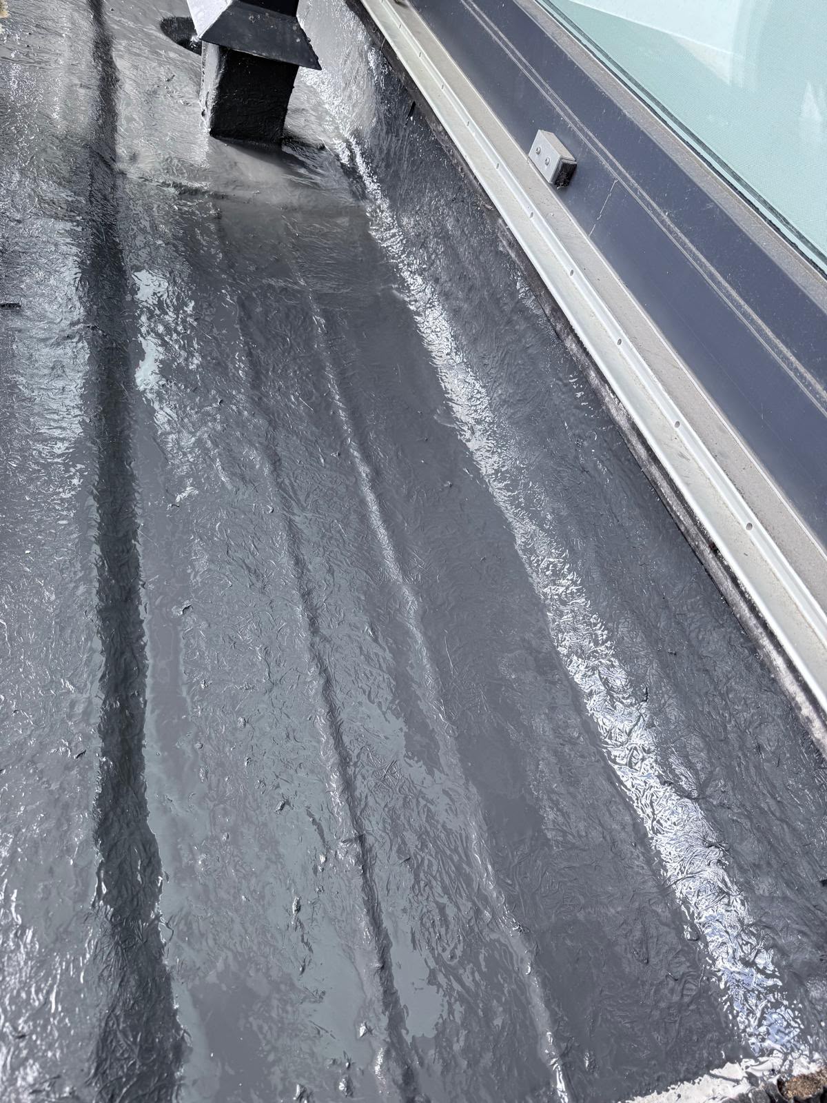 Liquid rubber valley repair beside a glazed roof section